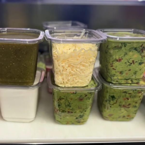 Containers of green salsa, shredded cheese, sour cream, and guacamole for Mi Taquito Grill.