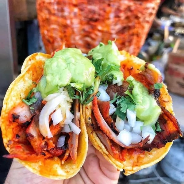 Two Mi Taquito Grill tacos with red meat, white onions, cilantro, and guacamole.