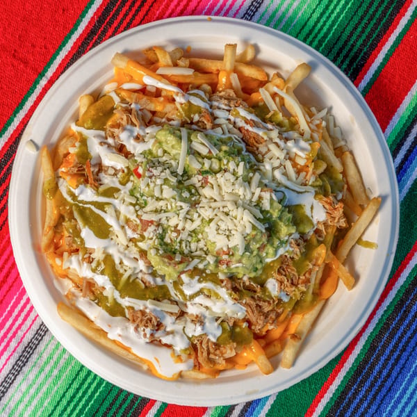 Mi Taquito Grill's Mexican fries, topped with cheese, guacamole, green sauce, and sour cream.