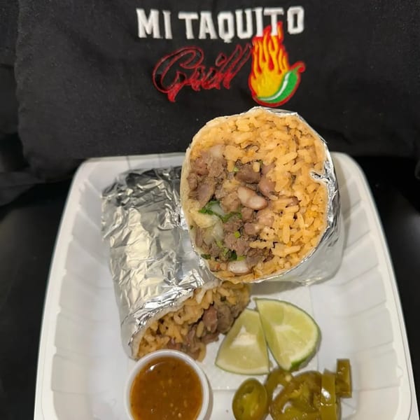 Two Mi Taquito Grill burritos, one cut open, with lime wedges, salsa, and jalapeños.